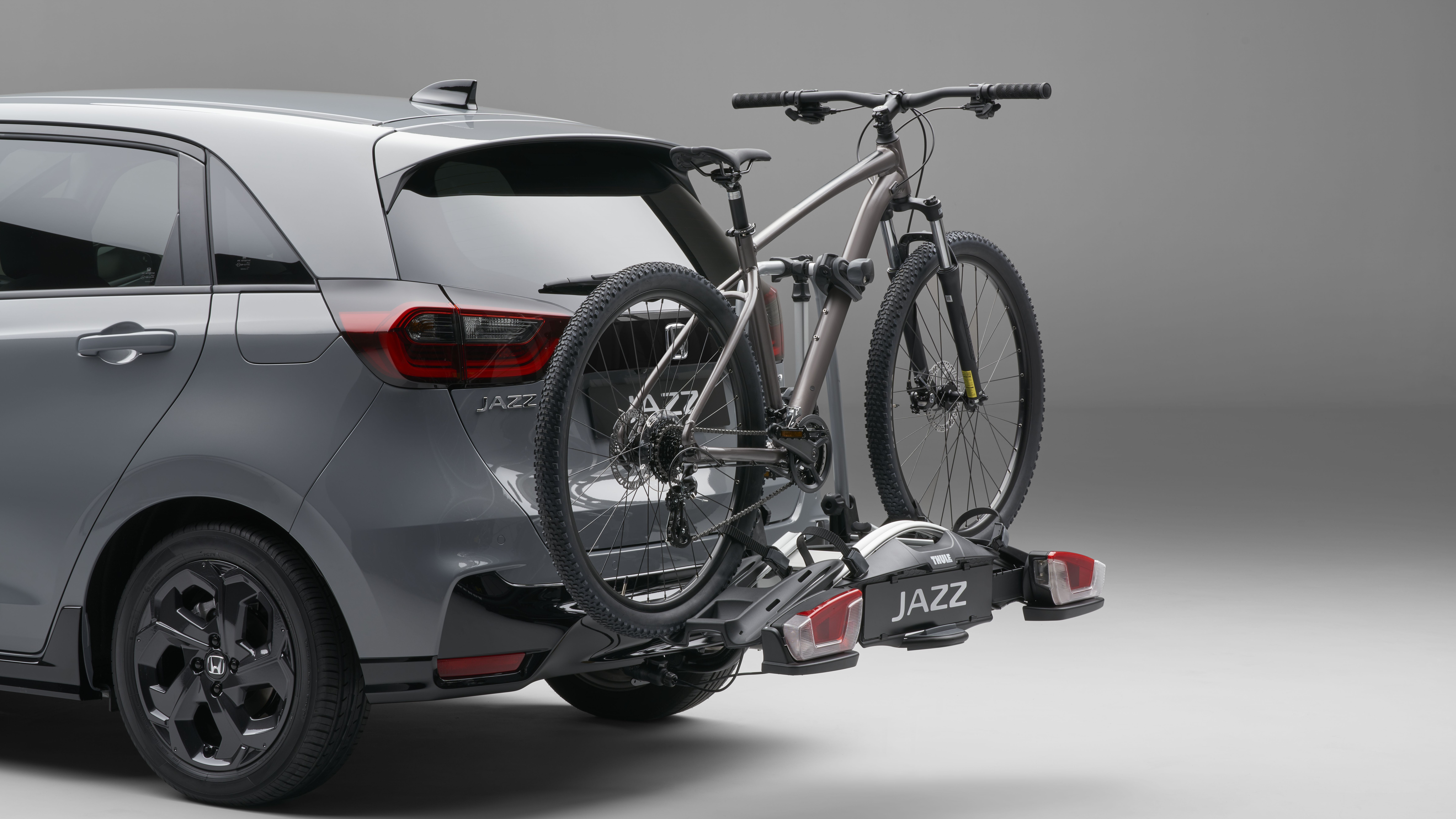 En grå Honda Jazz monterad med cykelhållare på dragkroken.